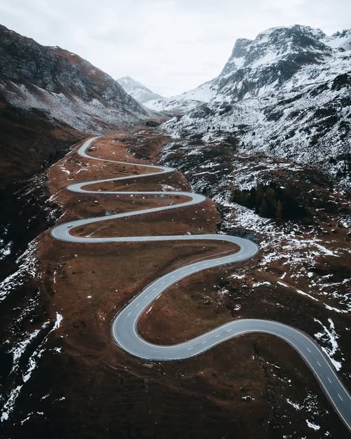 Route sinueuse au milieu de montagnes enneigées