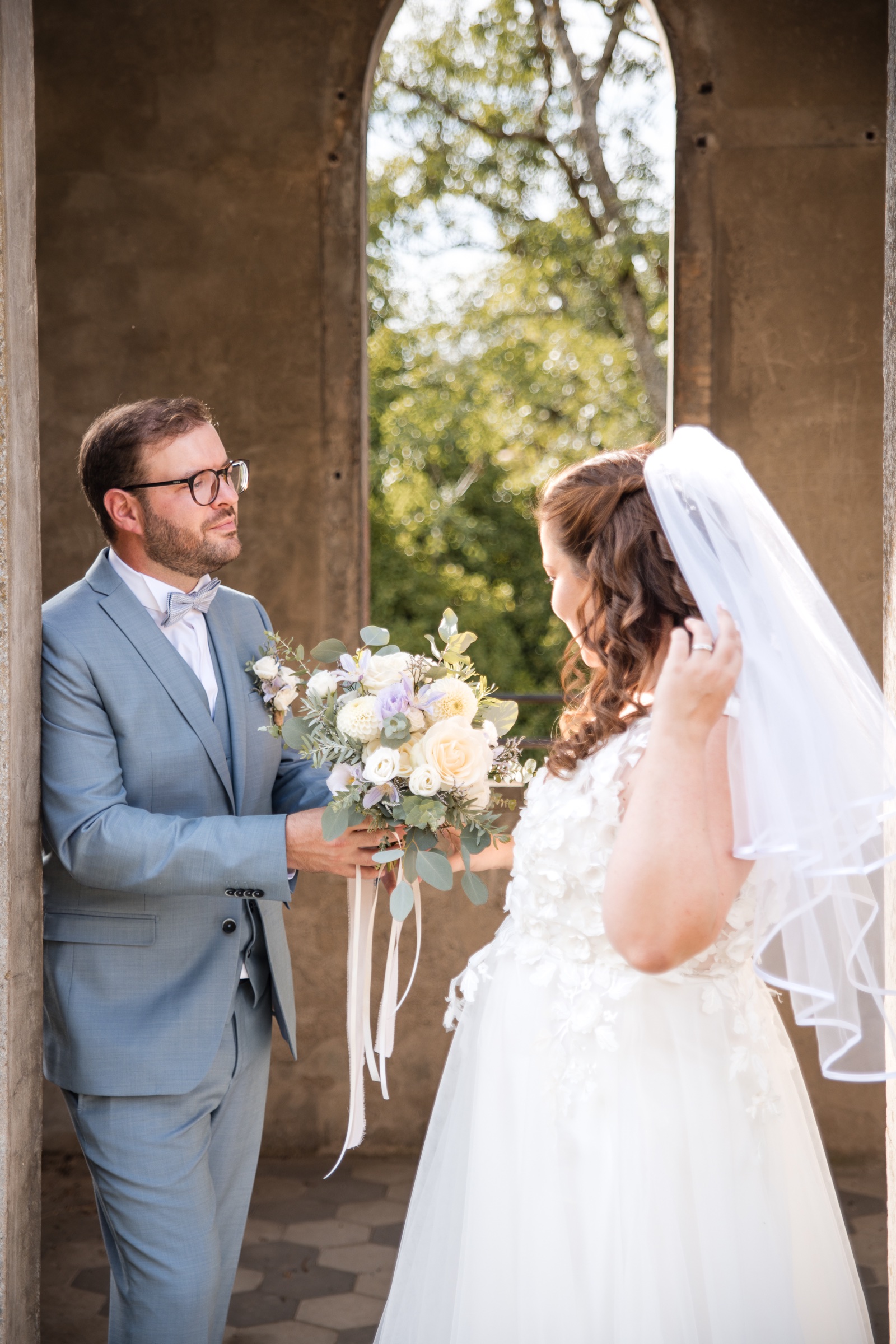 Les mariés réunis sous une arche avec leur bouquet